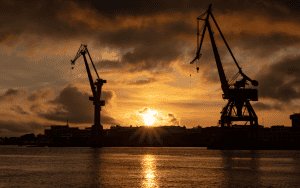 Vidlyftiga vallöften måste bli värdeskapande investeringar. Byggkranar under solnedgång i Göteborgs hamn